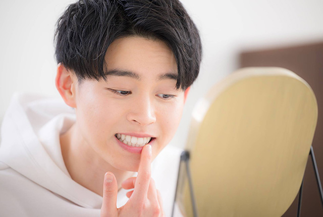 口元を鏡で見る男性