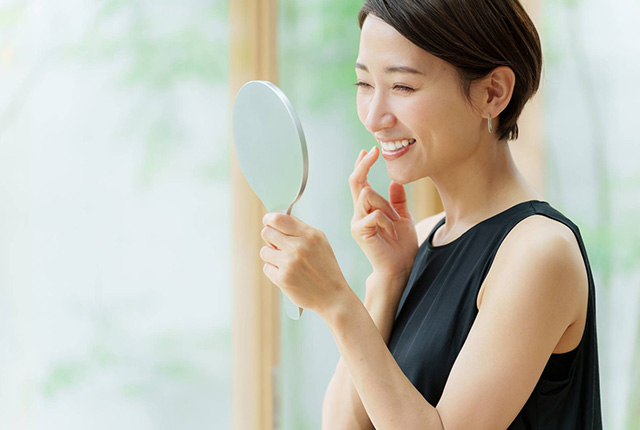 口元を鏡で見る女性